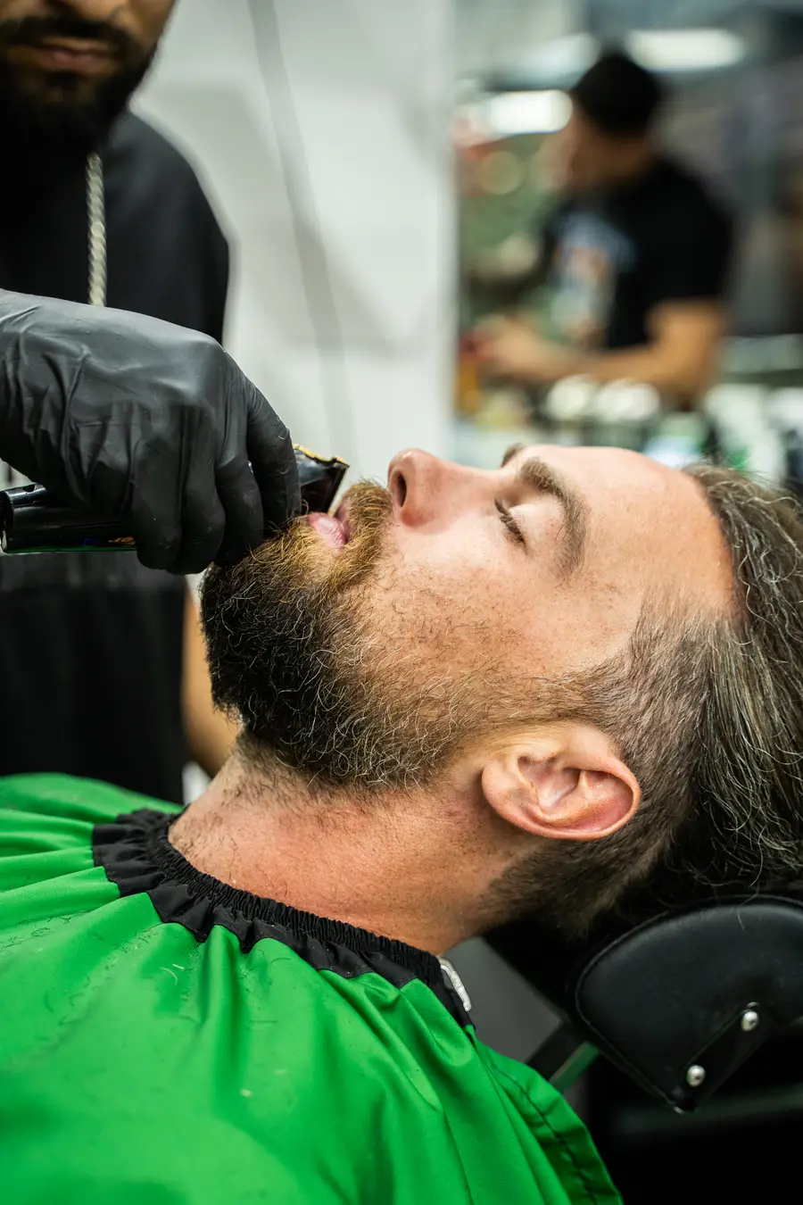 Beard trim, client reclined, trimmer under the chin